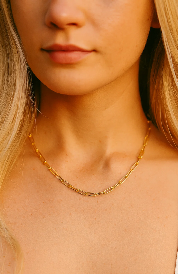Gold paperclip-link necklace worn by model at the neckline