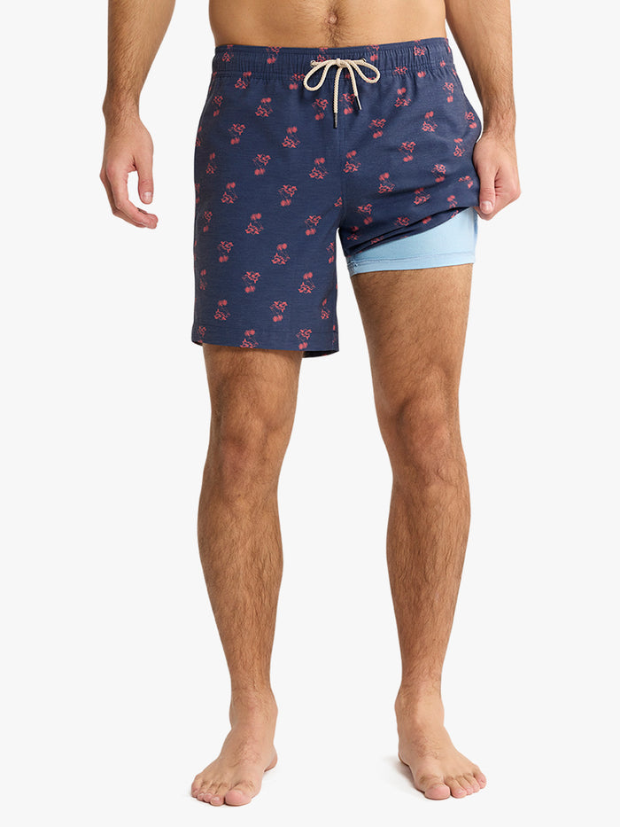 Man wearing navy swim shorts with red pattern on a white background