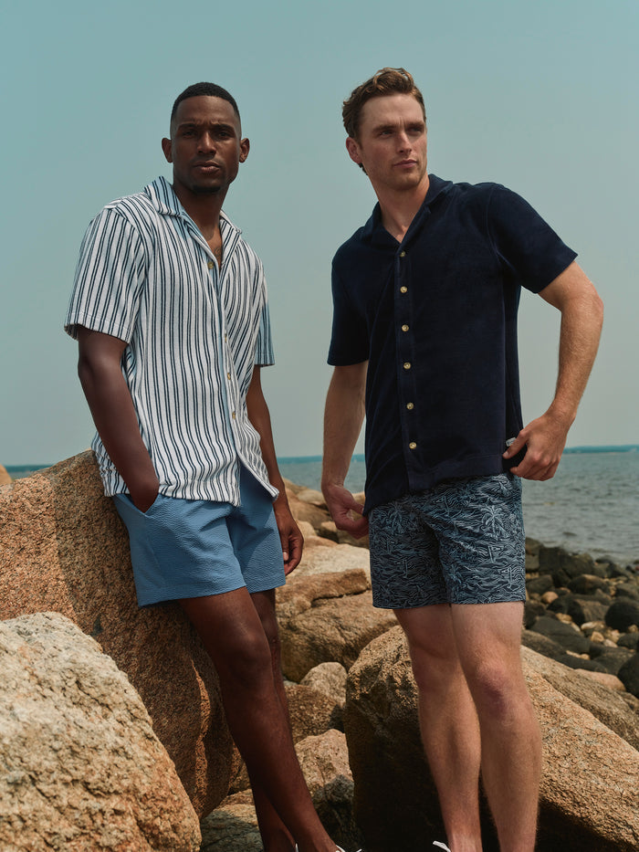 Two men standing on rocky beach with ocean in the background