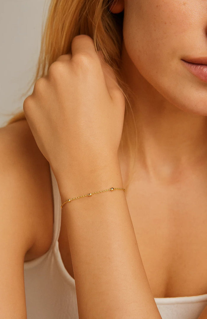 Gold-tone beaded link bracelet on wrist with adjustable chain
