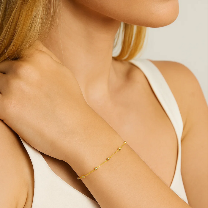 Gold-tone beaded link bracelet on arm with small round beads and clasp
