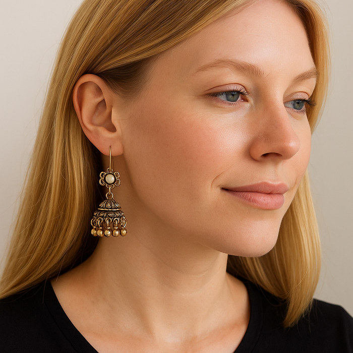 Gold-tone boho jhumka dangle earrings on model's ear, tiered bell shape