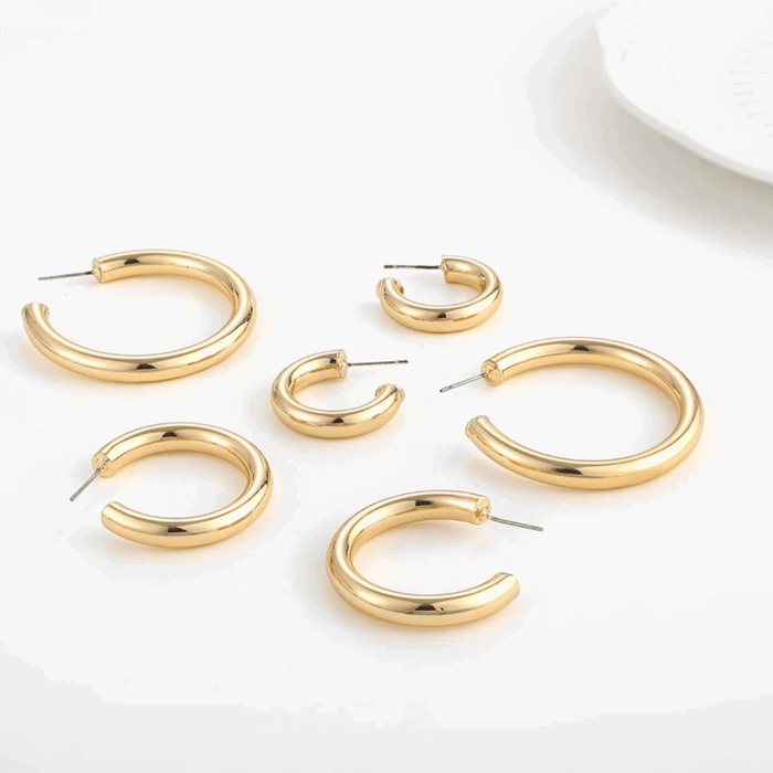 Gold-tone hoop earrings assortment with pin clasp, various round sizes, flat lay.