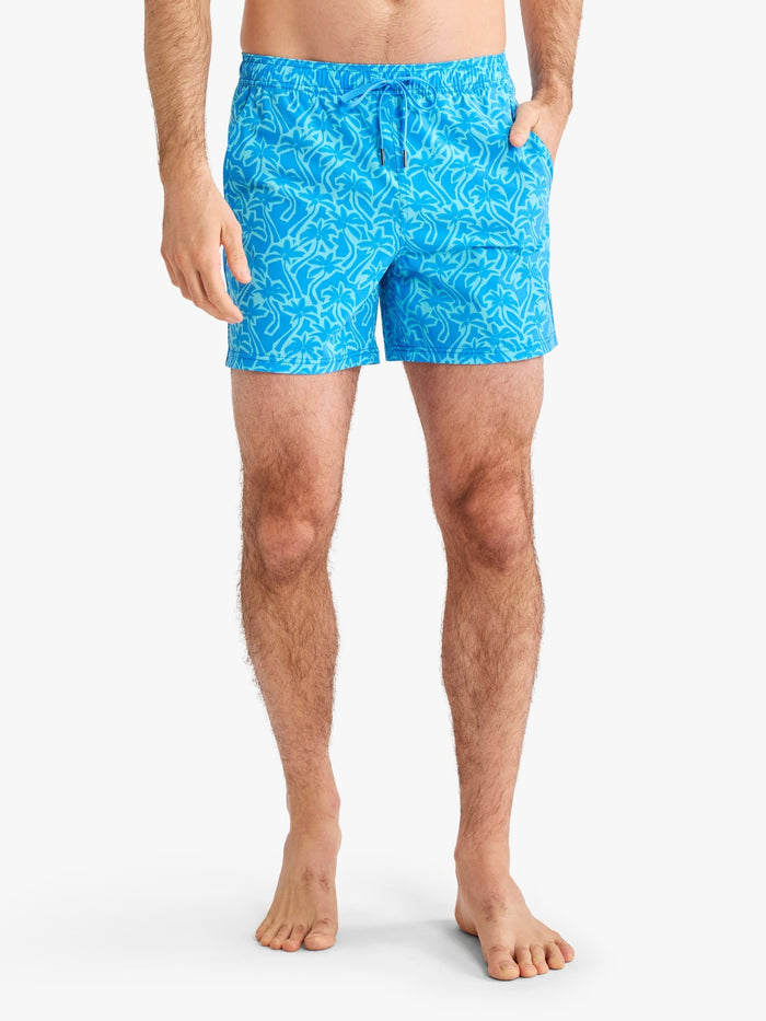 Person wearing blue swim shorts with a pattern on a white background