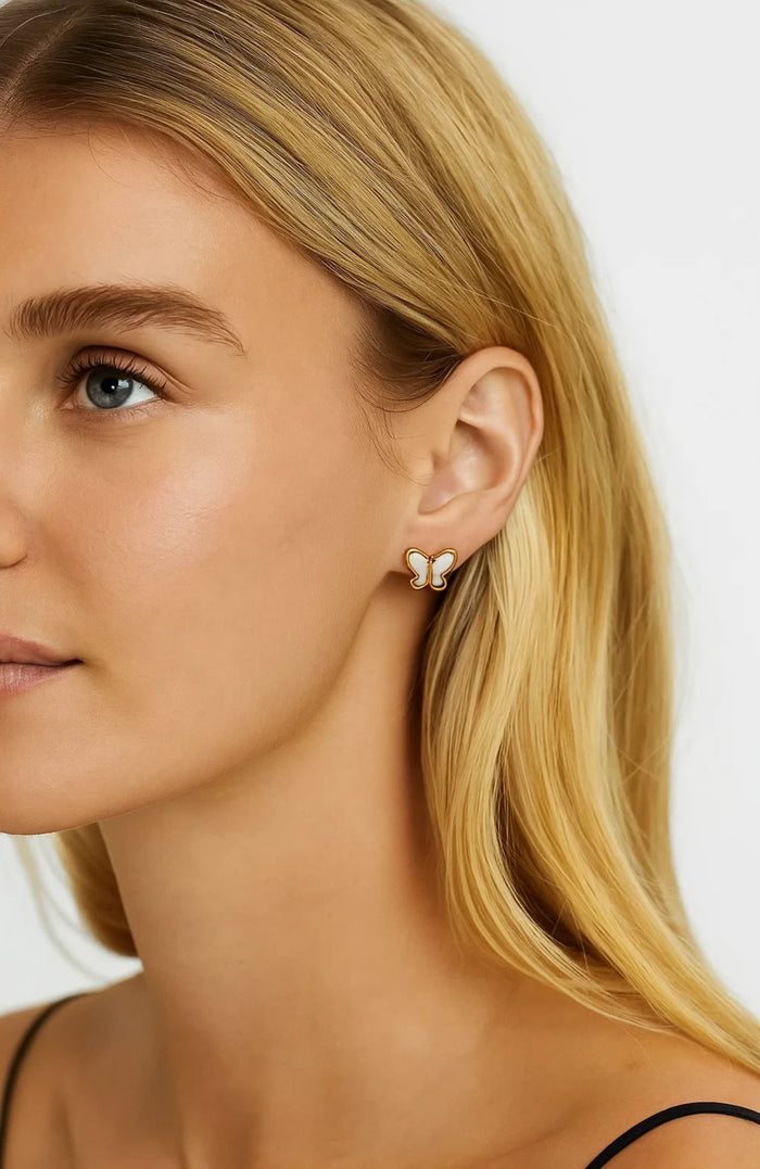 Gold butterfly stud earrings with mother-of-pearl inlay, close ear detail