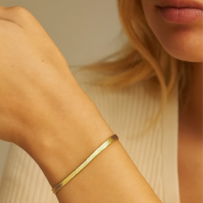 Gold-tone snake chain bracelet on wrist with slim adjustable clasp