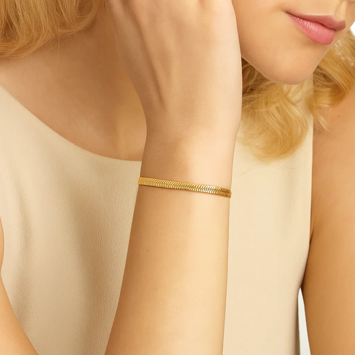 Gold-tone snake chain bracelet on wrist, sleek adjustable cuff style