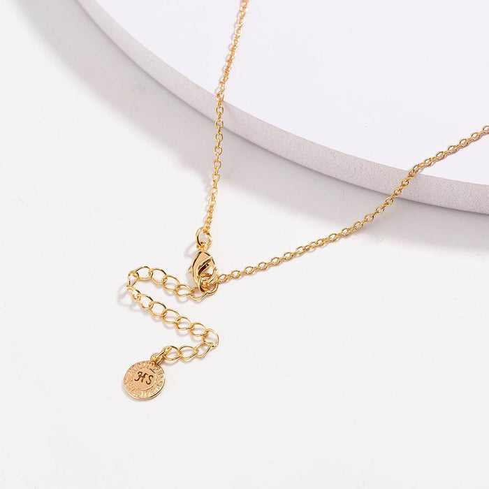Gold link necklace with black bead accents and round charm on extender