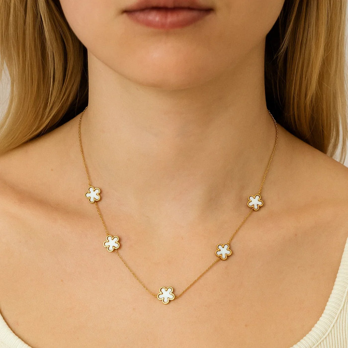 Gold-tone necklace with five flower charms, worn on neck (close-up)