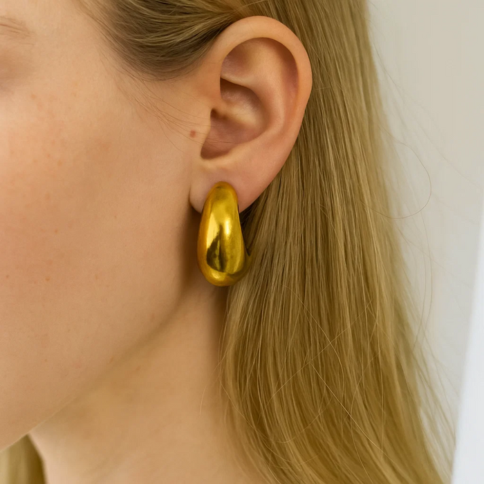 Gold dome huggie teardrop hoop earrings on ear