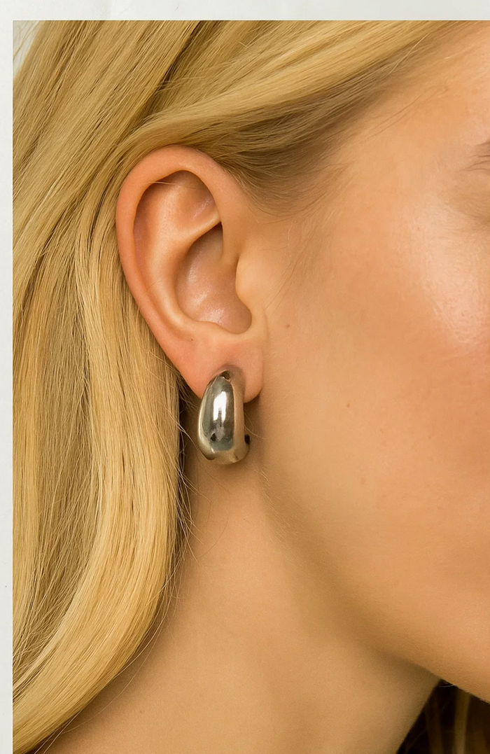 Silver dome huggie teardrop hoop earrings on ear