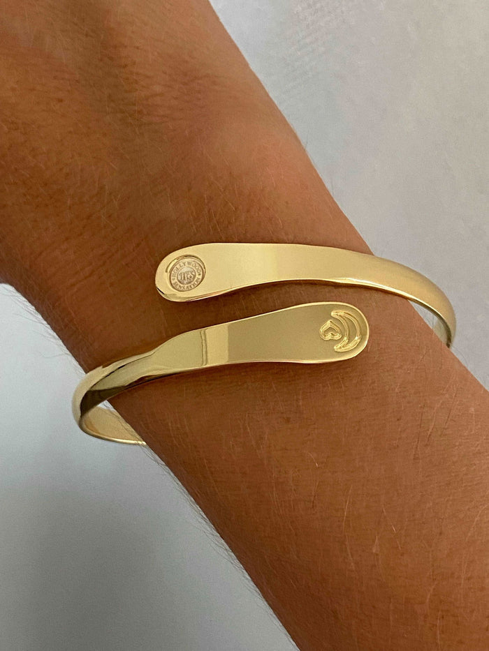 Gold engraved moon and heart cuff bracelet on wrist with round charm plate