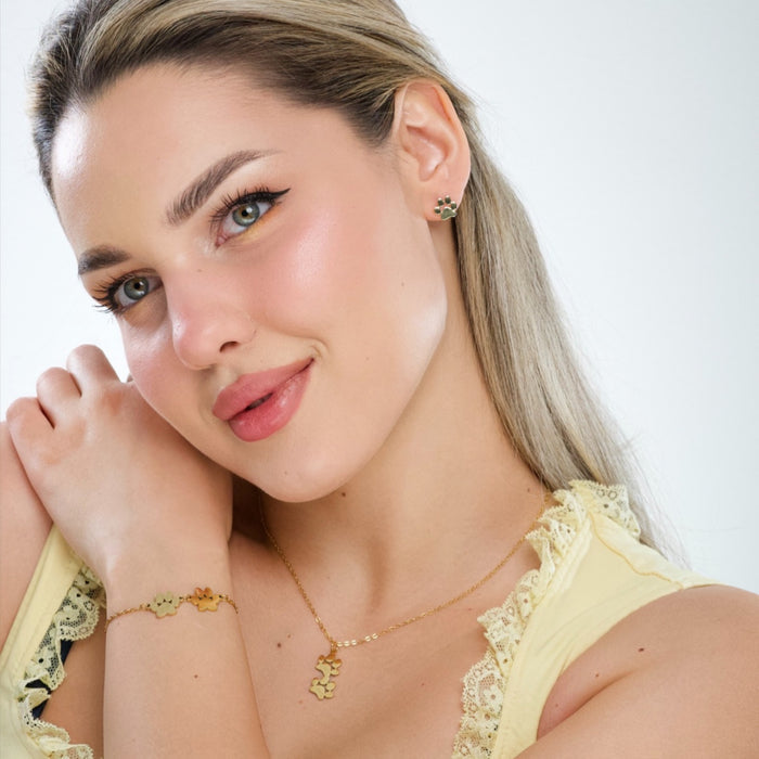 Gold double paw print pendant necklace, fine chain resting at collarbone.