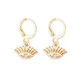Gold-tone huggie hoop earrings with dangling evil-eye charm and blue crystal