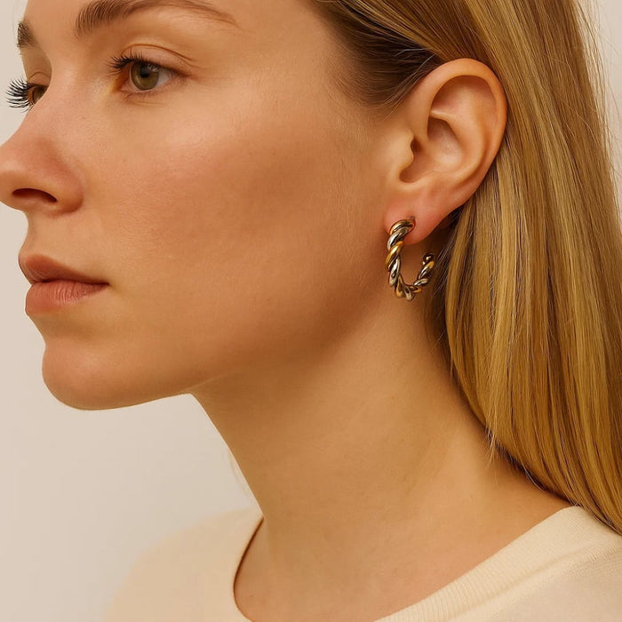 Two-tone twisted hoop earrings on ear, gold and silver mixed metal hoop style