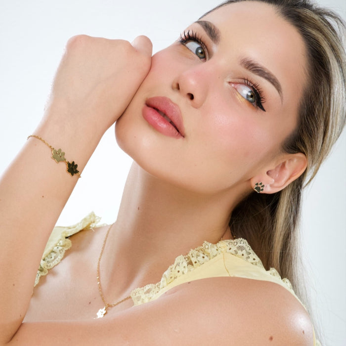 Gold paw print stud earrings on model near cheek, clustered paw pad design