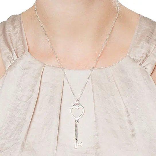 Heart and key pendant necklace worn on a light blouse with gathered neckline