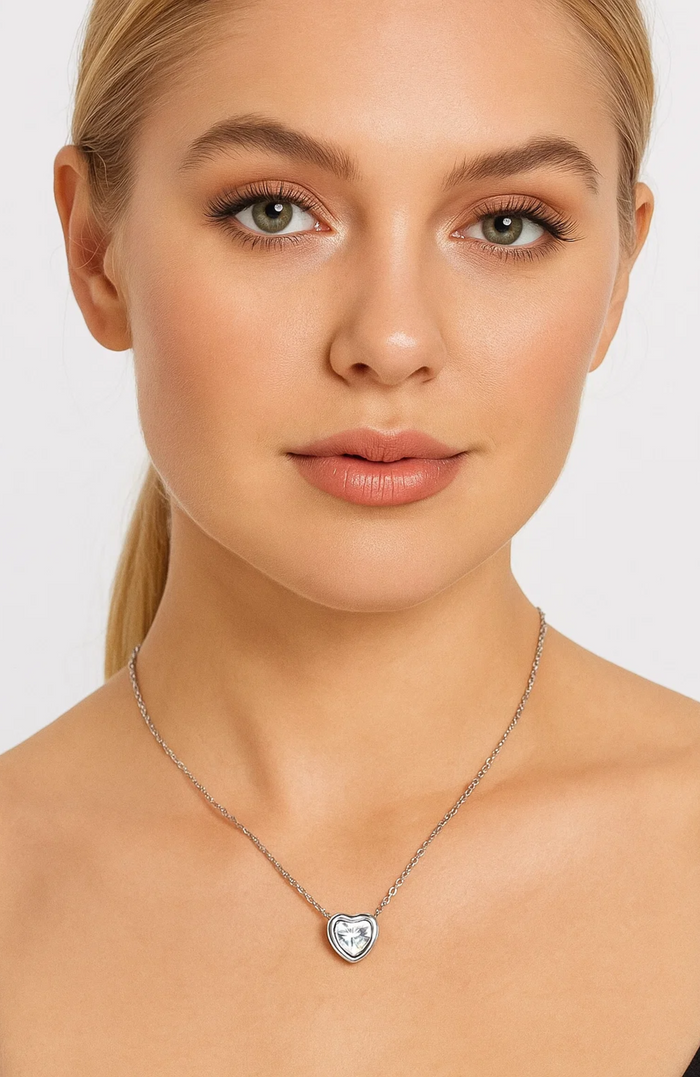 Silver-tone heart pendant necklace with clear cubic zirconia crystal, worn around neck