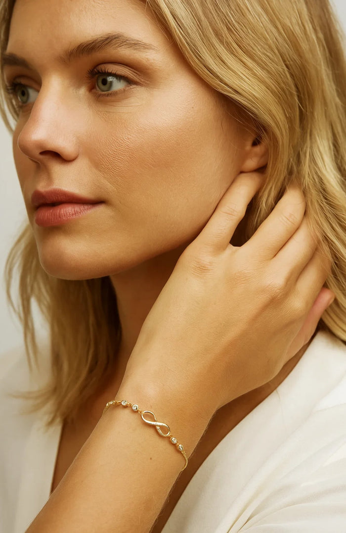 Gold infinity-link bracelet with small linked details, worn on wrist