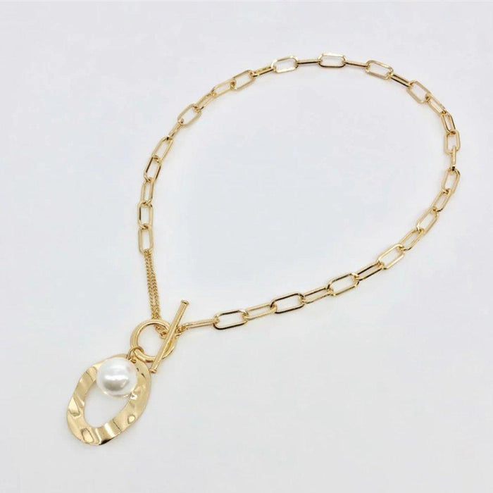 Gold link necklace with large oval pendant and white simulated pearl centerpiece
