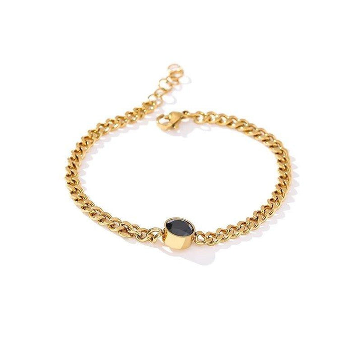Gold link chain bracelet with round black crystal charm at center