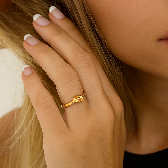 Gold love-knot ring on finger with twisted knot design, polished band