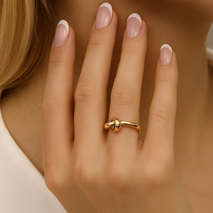 Gold love-knot ring on finger with twisted knot detail, polished finish