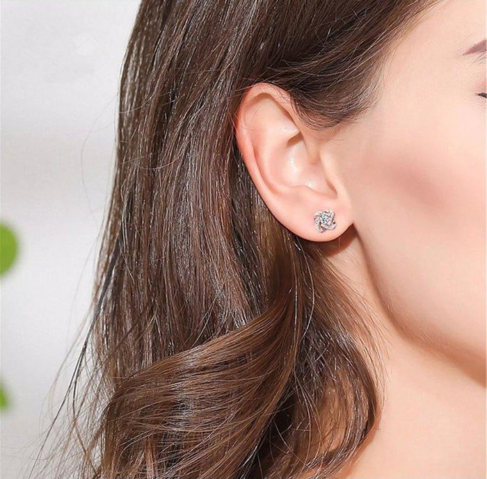 Rose gold love knot stud earrings with sparkling round stones on ear