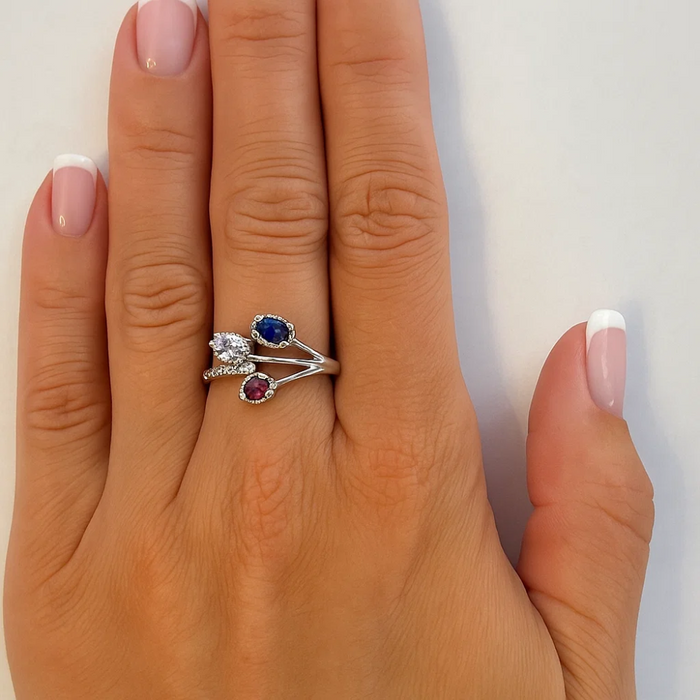 Silver-tone ring with blue oval CZ, small clear stones, and red/pink accent