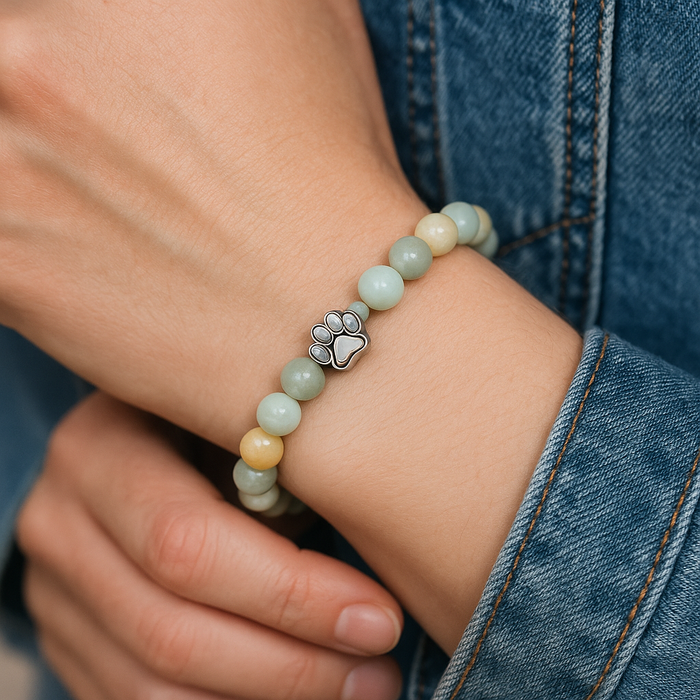 Beaded paw charm bracelet on wrist with pastel green and cream beads