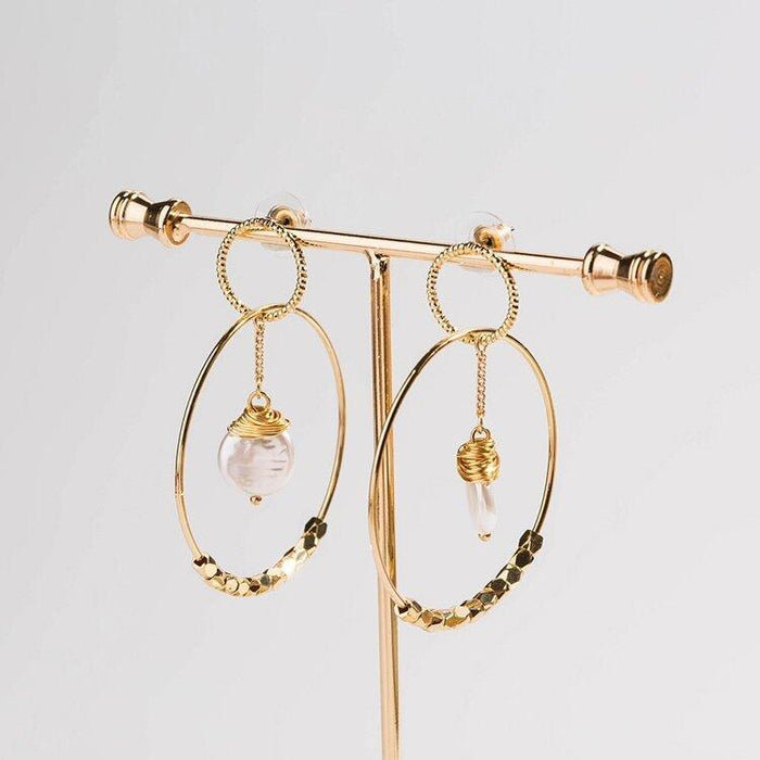 Gold tone double hoop earrings with pearl dangle charm and textured curved hoop band.