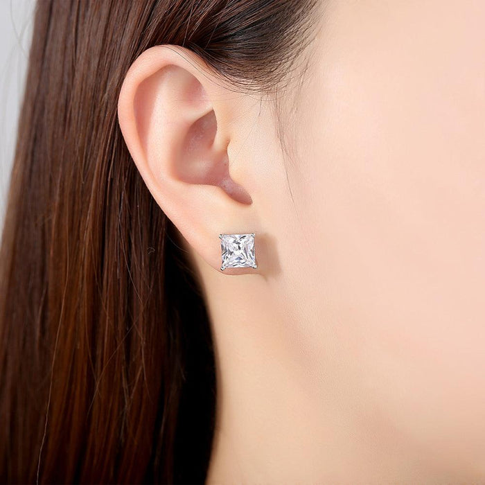 Princess-cut cubic zirconia stud earrings on ear, square clear stone in silver setting