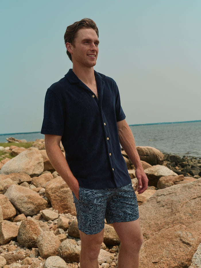 Man standing on rocky beach with ocean in the background