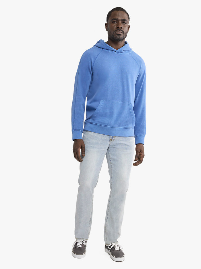 Man wearing a blue hoodie and light gray pants on a white background