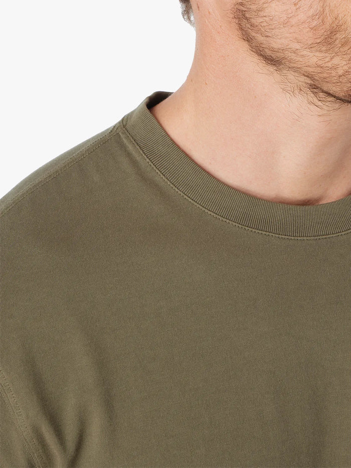 Close-up of a person wearing an olive green saltaire t-shirt against a white background