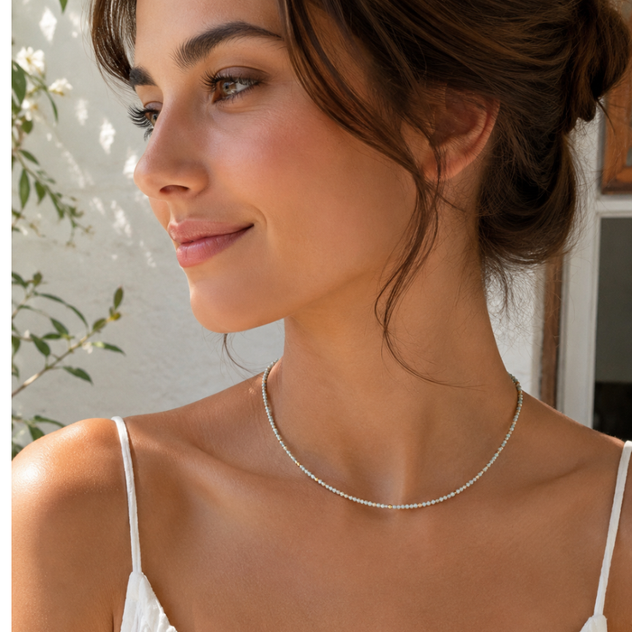 Seafoam beaded necklace resting at the collarbone with gold clasp detail and charm tag.
