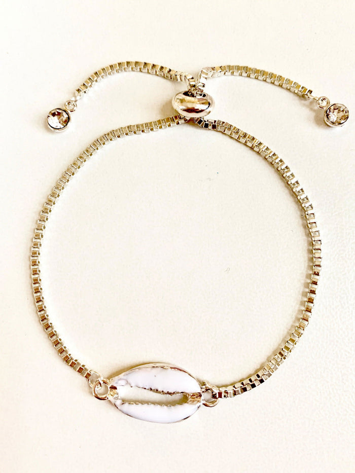 Gold seashell charm bracelet with oval seashell centerpiece and crystal end beads.