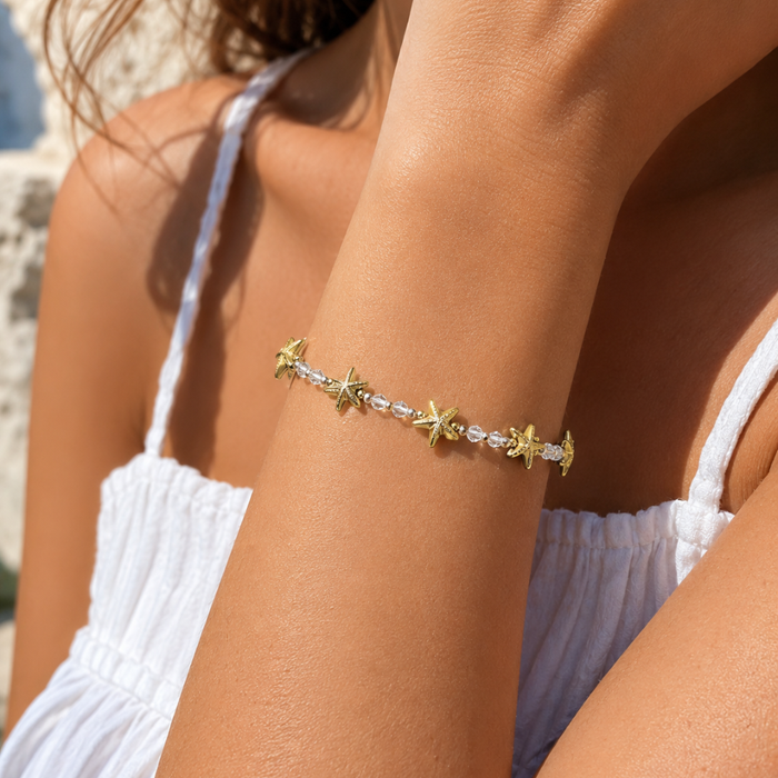 Starfish charm bracelet on wrist with gold and clear beads across chain