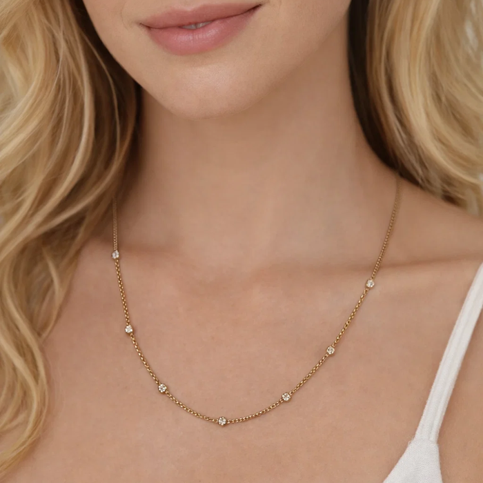 Close-up of gold bezel link necklace with round stones along chain