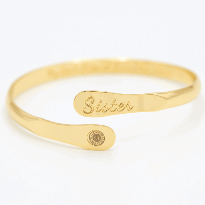 Gold sister engraved cuff bracelet with oval nameplate and round emblem