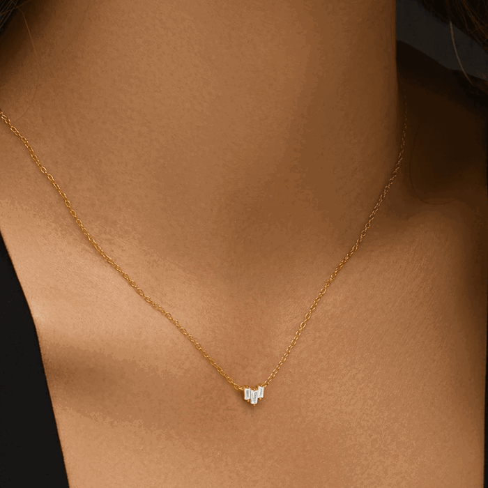 Gold-tone necklace on neckline, three emerald-cut cubic zirconia stones in V pendant