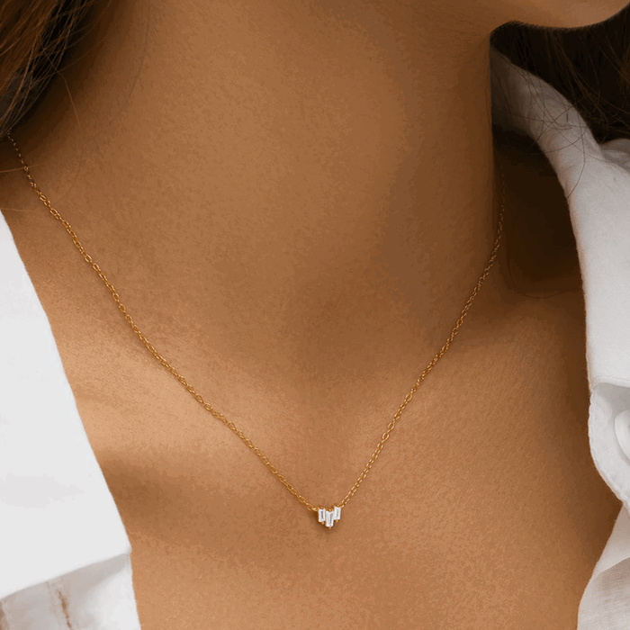 Gold-tone necklace on neckline, three emerald-cut cubic zirconia stones pendant