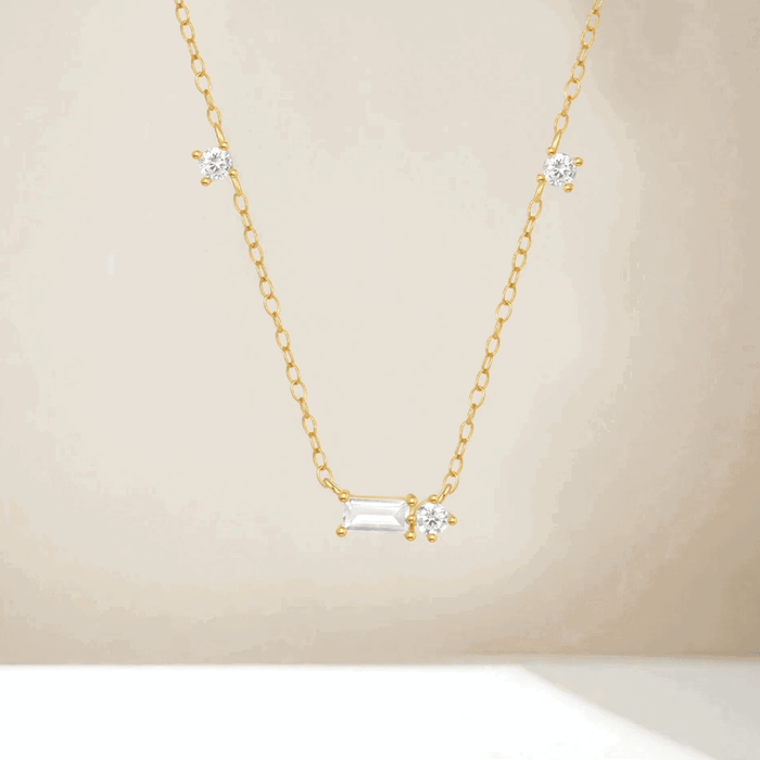 Gold tone cubic zirconia necklace with three round stones and a central emerald-cut charm