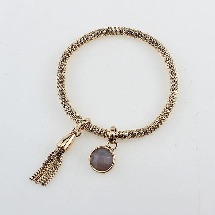 Gold-tone tassel charm bracelet with oval mauve stone pendant and open chain link