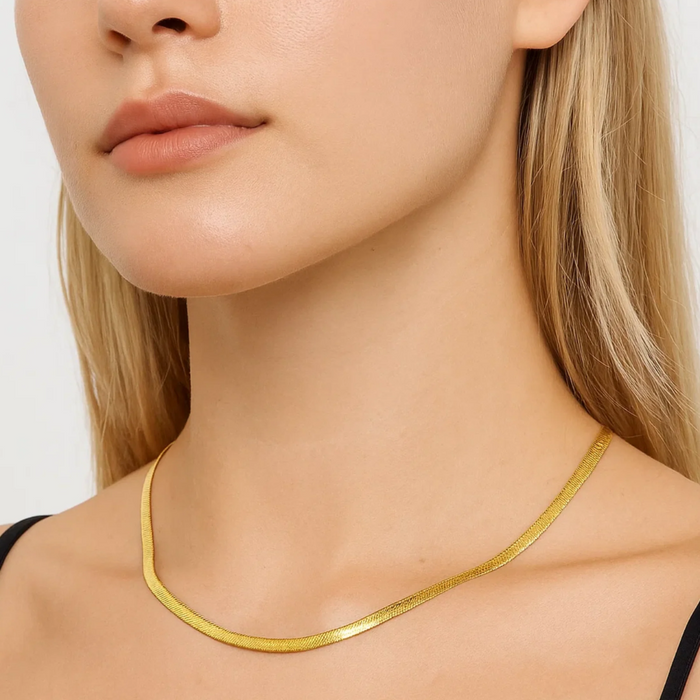 Gold snake chain necklace with slim links, worn around the neck
