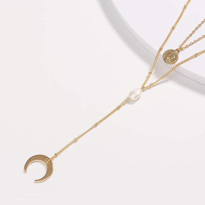 Gold layered necklace with crescent moon pendant, coin charm, and pearl bead
