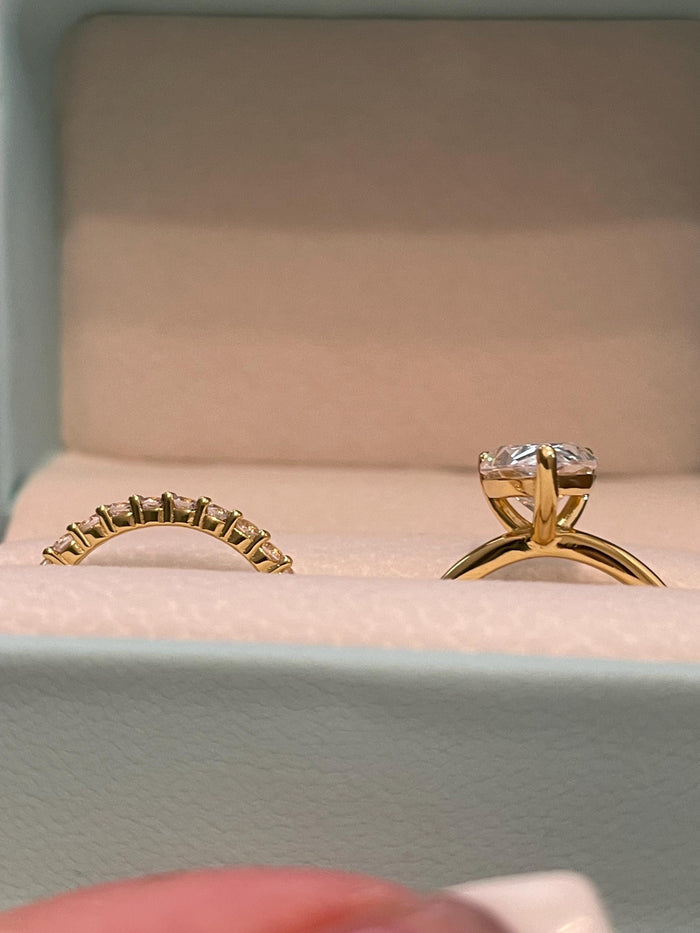 May include: Two gold wedding bands, one with a large round diamond and the other with a row of smaller diamonds.