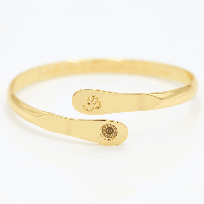 Gold yoga bracelet with engraved Om symbol plate and small round logo on side